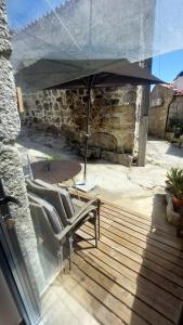 a patio with two chairs and an umbrella at Casa da Fraga in Soajo