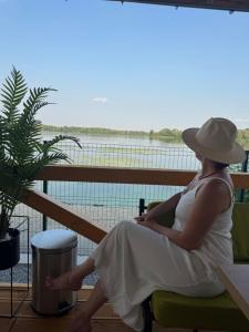 a woman in a white dress and hat sitting on a chair at Будинок на Дніпрі in Kozin