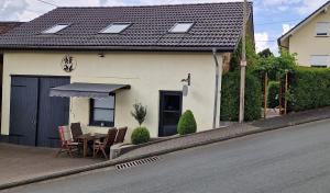 a house with a table and chairs next to a street at Ferienwohnung Moos in Haiger