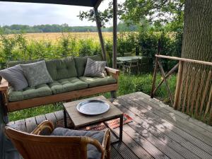a green couch sitting on a deck with a table at Vakantieboerderij Den Deter in Meddoo