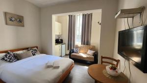 a bedroom with a bed and a television and a chair at David Hameleh House in Netanya
