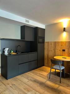 a kitchen with black cabinets and a table and a chair at Ma Chérie in Livigno +4 photos