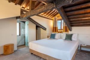 a bedroom with a large white bed and wooden ceilings at Hotel San Samuele in Venice