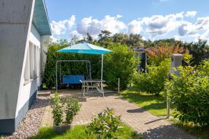 a patio with a table and an umbrella at Bungalow am Waldrand in Barth