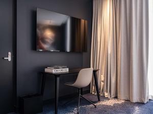 a room with a desk and a television on a wall at Novotel Sydney Cabramatta in Cabramatta
