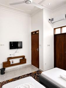 a bedroom with two beds and a tv on the wall at Lamu Creek Hotel in Lamu