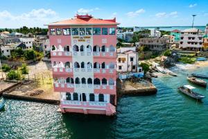 a pink building in the water next to a city at Lamu Creek Hotel in Lamu