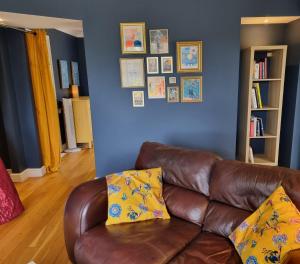 a living room with a brown leather couch with yellow pillows at A quiet gem just outside Oundle in Oundle