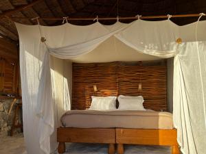 a bedroom with a canopy bed with white pillows at Manga Bay Lodge in Toliara