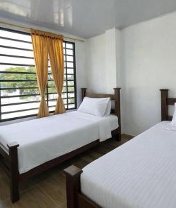 two beds in a room with a window at Apartamentos El Remanso in Mariquita