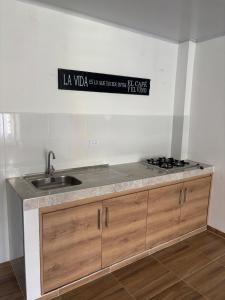 a kitchen counter with a sink and a sign on the wall at Apartamentos El Remanso in Mariquita