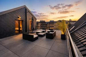 a rooftop patio with couches and tables on a building at Les Suites de Nanesse in Liège