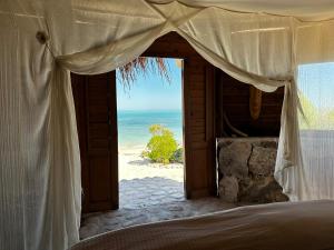 a bedroom with a bed and a view of the beach at Manga Bay Lodge in Toliara