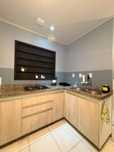 a large kitchen with two sinks and a window at Hidromassagem cromoterapia ar condicionado lareira in Imbé