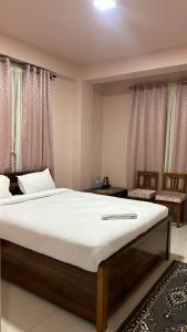 a bedroom with a large bed with white sheets at Serenity View Stay in Shillong