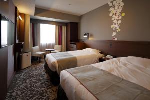 a hotel room with two beds and a television at Hotel Monte Hermana Fukuoka in Fukuoka