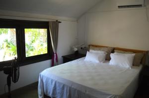 a bedroom with a large white bed with a window at Azeer's in Arugam Bay