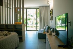 a bedroom with a bed and a tv and a couch at Villa Naluri - Studio Iamandu A001 in Japaratinga
