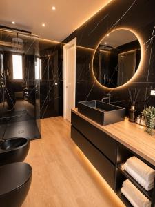 a black bathroom with a sink and a mirror at Le Charme Luxury Suite in Patti