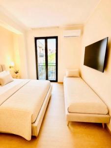 a bedroom with two beds and a flat screen tv at Le Charme Luxury Suite in Patti