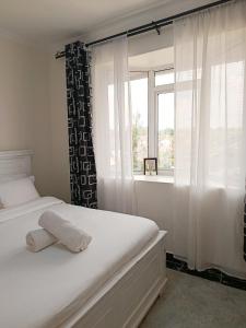 a bedroom with a white bed with a window at Mura suites homes in Nakuru