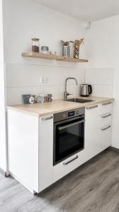 a white kitchen with a stove and a sink at Cozy Apartment with Terrace & Free Parking in Würzburg