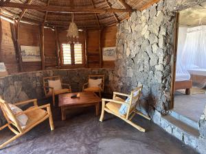 a room with chairs and a table and a stone wall at Manga Bay Lodge in Toliara