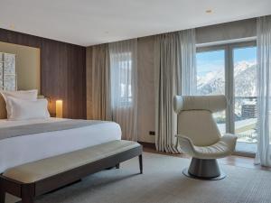 a bedroom with a bed and a chair and a window at Maya Hôtel Courchevel 1850 in Courchevel +73 photos