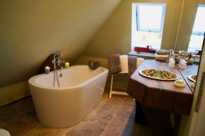 un bagno con una grande vasca bianca e un lavandino di Ferienhaus nahe Ostsee mit Sauna, Kamin & eingezäuntem Garten,Hund willkommen a Rabenholz Altre 24 foto