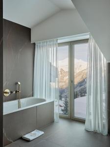 a bathroom with a tub and a large window at Maya Hôtel Courchevel 1850 in Courchevel