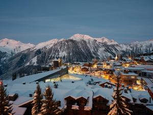 a town in the snow with mountains in the background at Maya Hôtel Courchevel 1850 in Courchevel