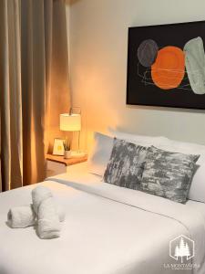 a hotel room with a bed with white sheets at La Montañosa at Brenthill Baguio Condo near City Center in Baguio