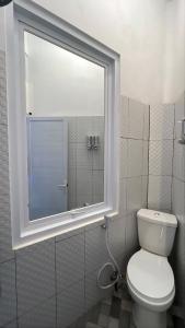 a bathroom with a white toilet and a window at Naeera Inn Wonosobo Dieng in Kalibeber