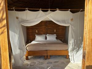 a bedroom with a canopy bed with white sheets and pillows at Manga Bay Lodge in Toliara +11 photos