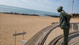 a statue of a man standing on the beach at l 'Escapade Atlantique in Saint-Nazaire +3 photos