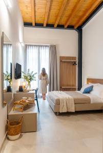 a woman standing in a bedroom looking out the window at Antiche Cantine Bed & Breakfast in Alcamo