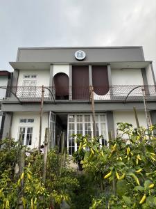 a white house with a balcony with a clock on it at Naeera Inn Wonosobo Dieng in Kalibeber +19 photos