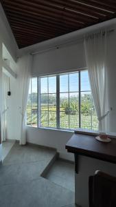 a room with large windows and a table with a view at Naeera Inn Wonosobo Dieng in Kalibeber
