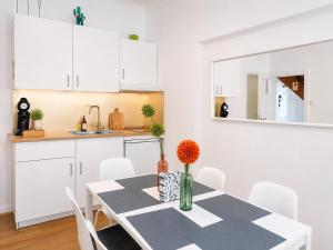 Una cocina blanca con una mesa y gabinetes blancos. en The garden flat, en Luxemburgo