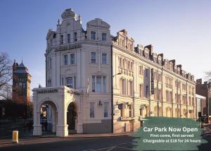 a large white building with a clock tower on a street at The Angel Hotel in Cardiff