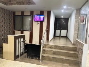 a lobby with a tv on the wall and stairs at Grand Almada Inn in Lucknow +17 photos
