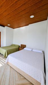 a bedroom with two beds and a wooden ceiling at Suite frente al Mar con Acceso Directo a la Playa in Ballenita