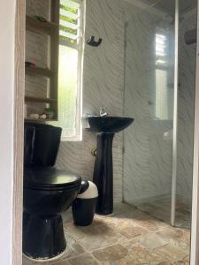 a bathroom with a black toilet and a sink at Santo Cristo in Tena +9 photos
