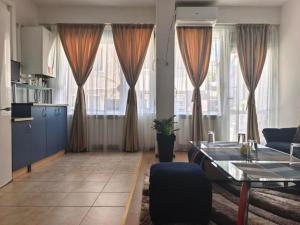 a living room with a table and some windows at Hristean Apartment Petrich in Petrich