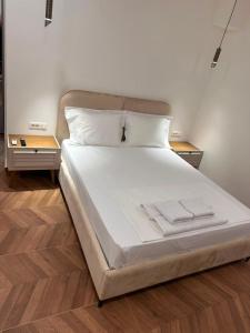 a large bed with white sheets and two night stands at Zac's Rooms in Dukat