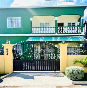 a green house with a black gate with graffiti at Olive Breeze III in Runaway Bay