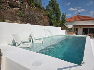 a swimming pool with chairs and a house at Casa Lage da Pena in Geres