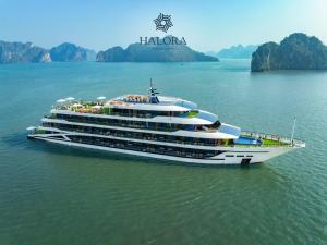 a large cruise ship in the water with mountains in the background at Halora Kairos Cruise in Ha Long