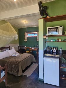 a bedroom with a bed and a kitchen and a table at Pousada Ceu e Serra in Carrancas