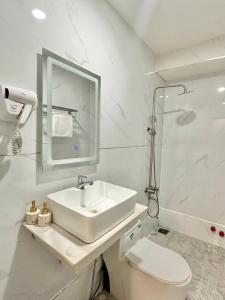 a white bathroom with a sink and a toilet at Phú Gia Hotel 464 Nguyễn Văn Linh in Ho Chi Minh City